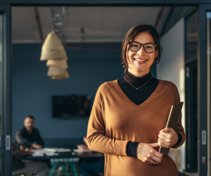 woman smiling and holding a closed laptop